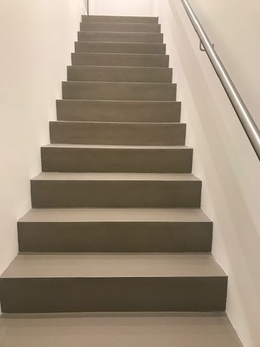 Graur treppe mit weissen Wänden und metallischem Handlauf